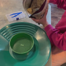 Children sorting gemstones and gold from paydirt during indoor learning activity