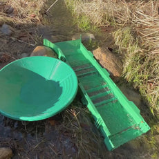 Green gold pan and accessories ready for gold panning practice in natural environment